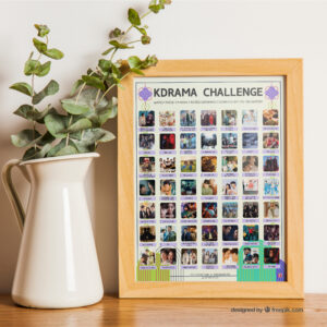 A vibrant poster on a tabletop titled "KDRAMA CHALLENGE" displays 49 Top Rated Kdramas within a wooden frame. The poster features a grid of images and drama titles. On the table, there is a houseplant to the left of the frame.